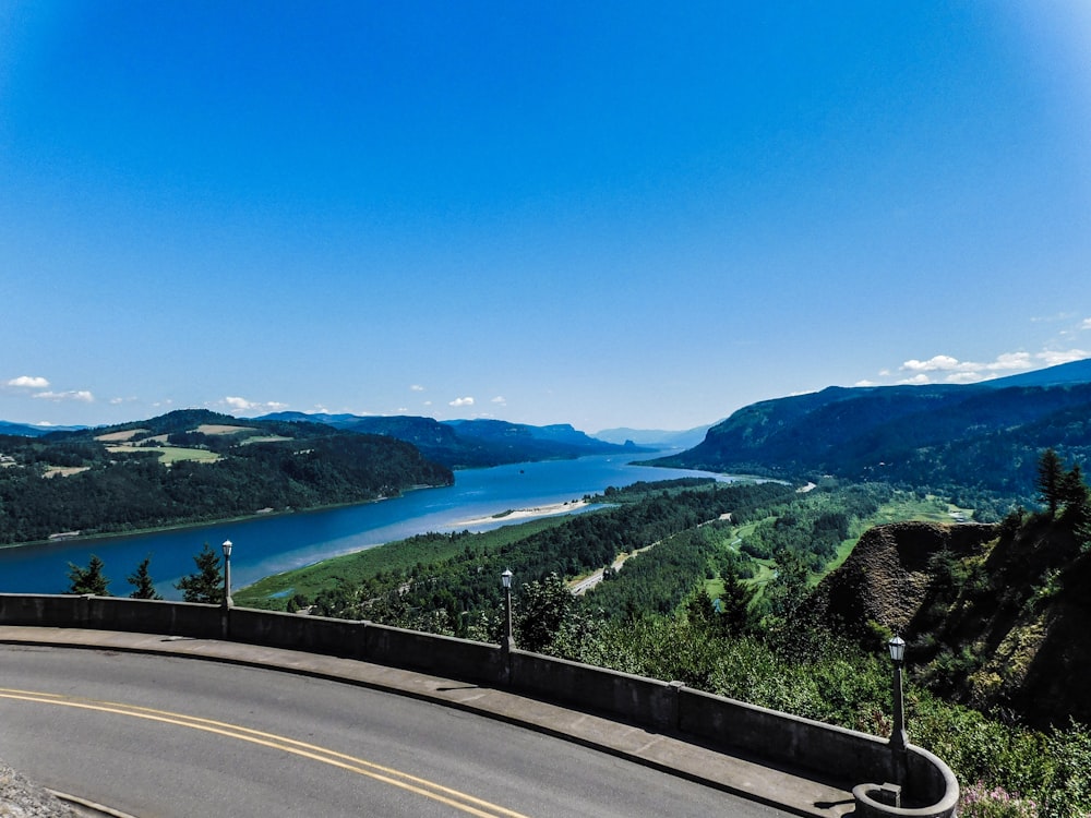 a curved road with a lake in the distance