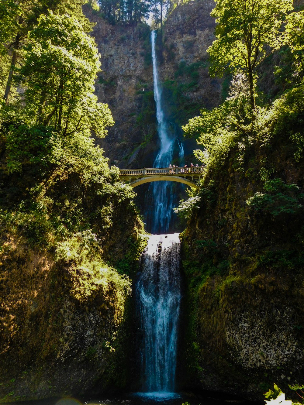 a waterfall with a bridge in the middle of it