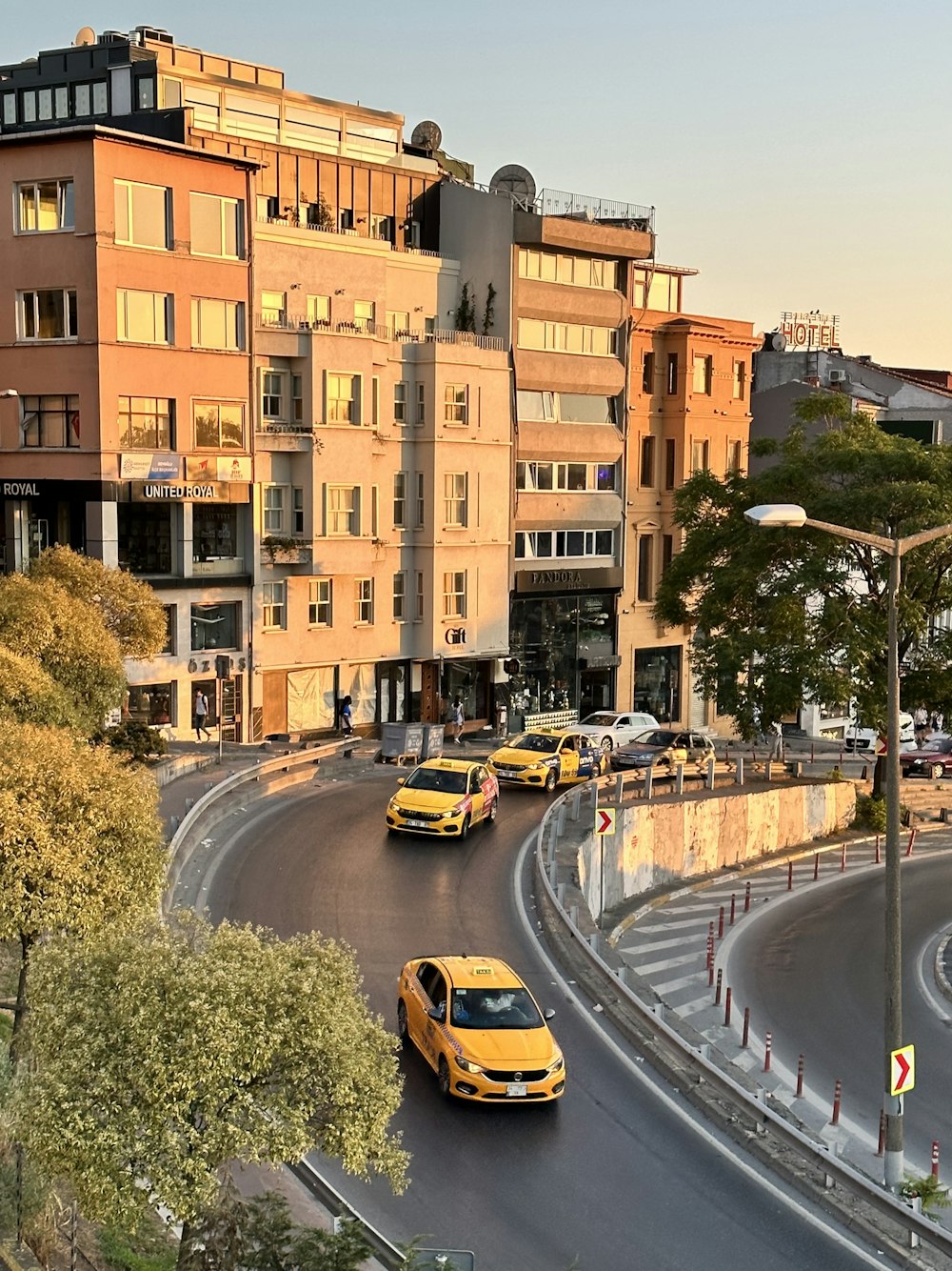 a group of cars driving down a street next to tall buildings