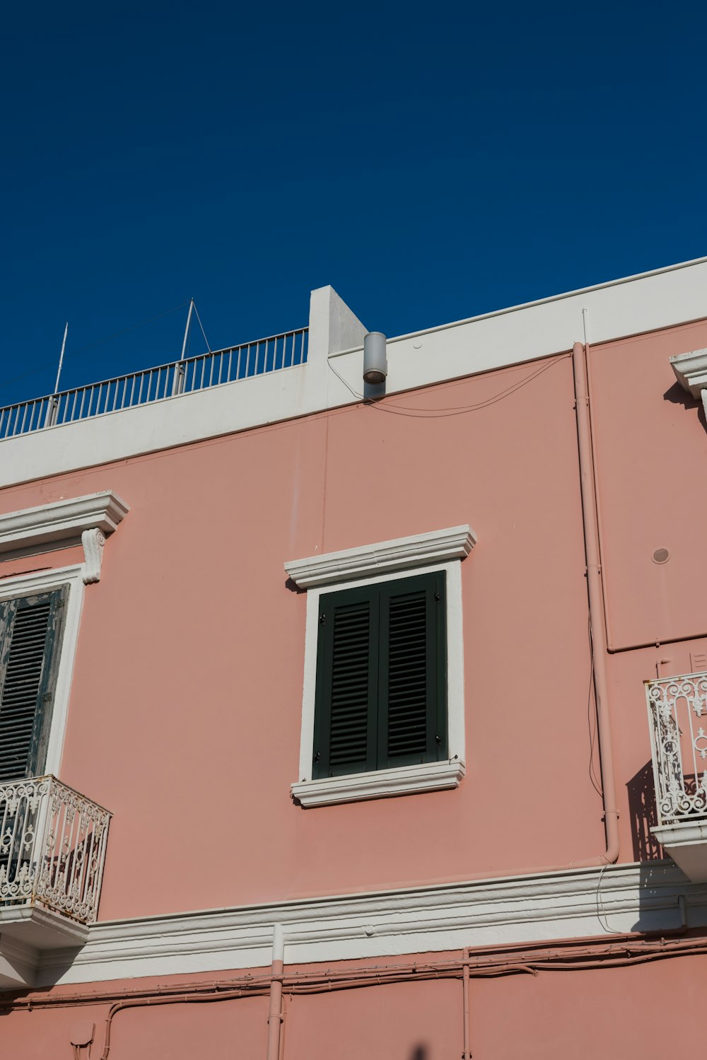 a pink building with two balconies and a balcony
