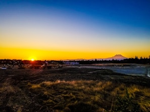 Sunset over a mountainous mining landscape with mining trucks.
