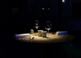A dimly lit dinner table set for two, shadows hinting at tension.