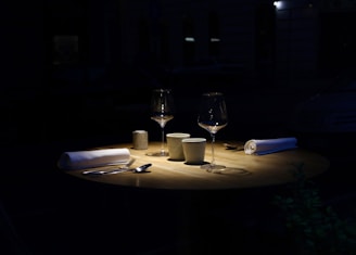 A softly lit table set for two, with candles and wine glasses, evoking an intimate dinner atmosphere.