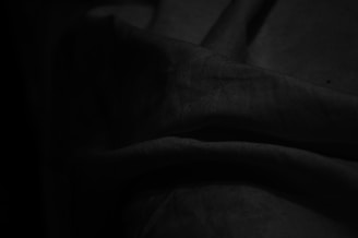 Abstract shadows cast by a gently draped white fabric against a deep black background with subtle accents of copper.