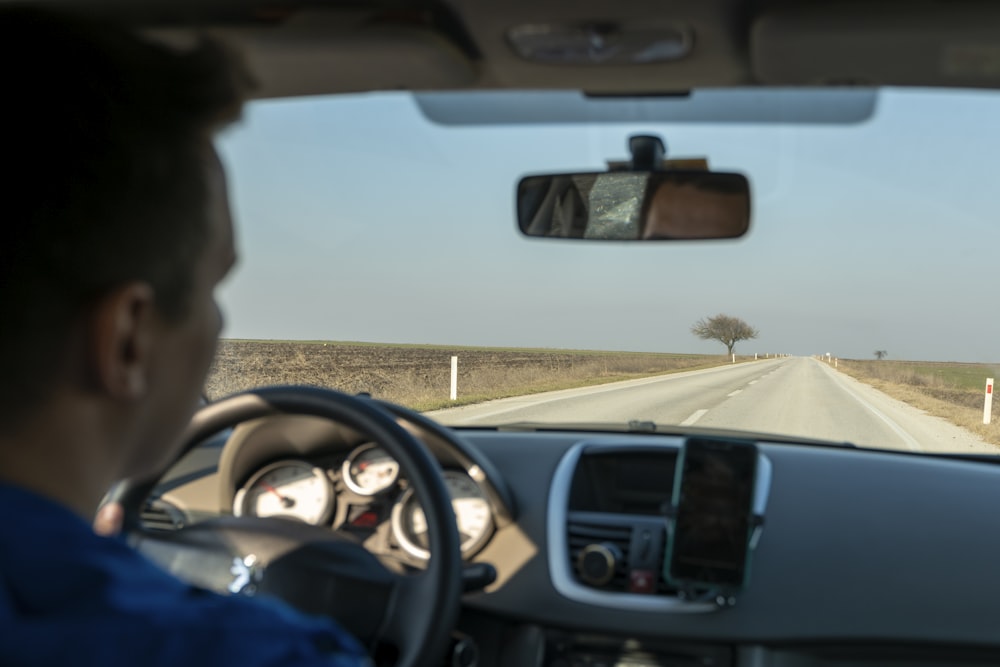 a man driving a car down a country road