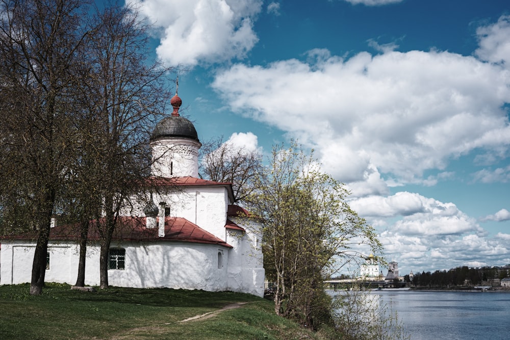 a white building with a red roof next to a body of water