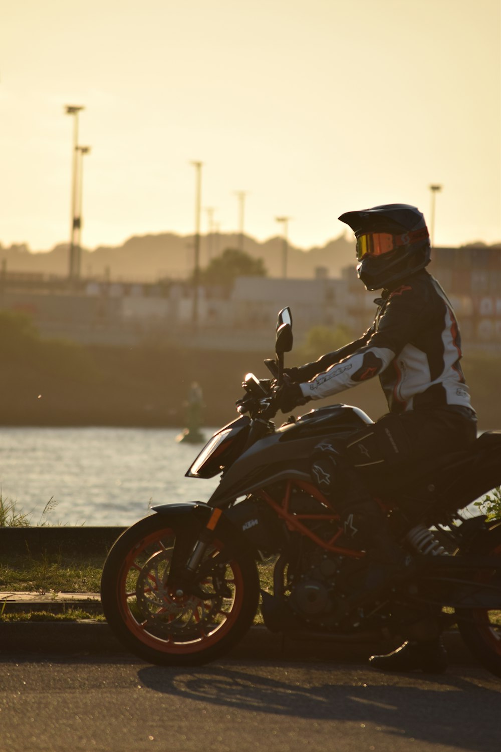 a man riding a motorcycle down a street next to a lake