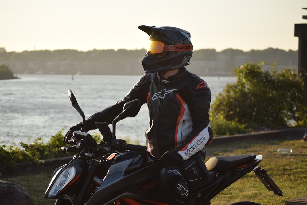 a person sitting on a motorcycle in front of a body of water