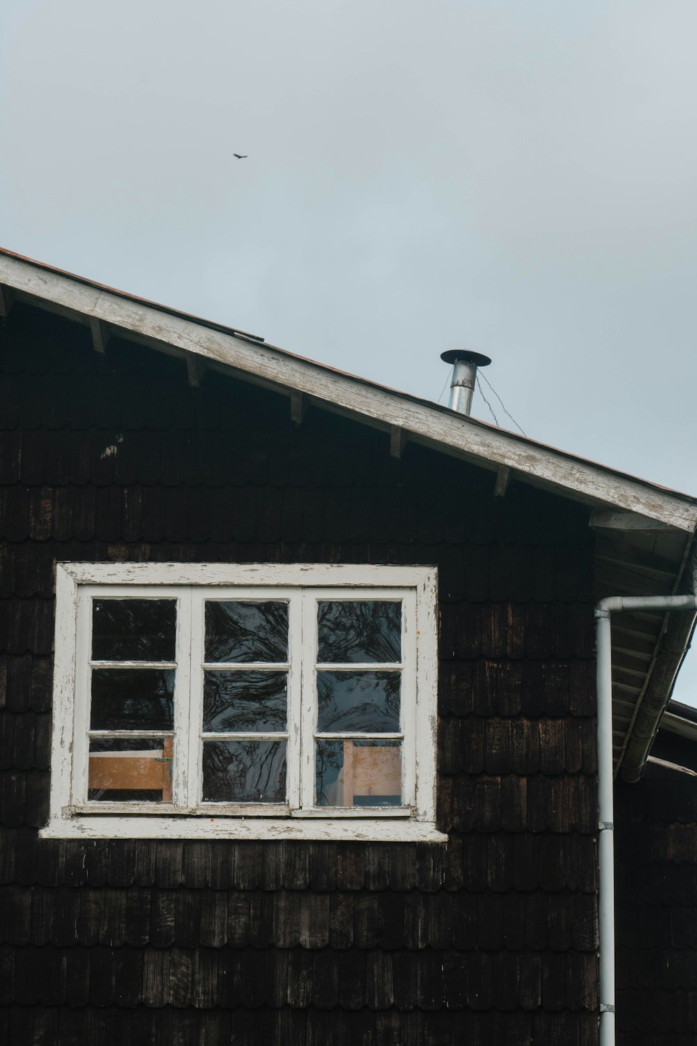 a black house with a white window and a weather vane