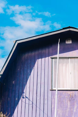 A close-up of a house roof painted in bright, eye-catching colors under a clear blue sky.