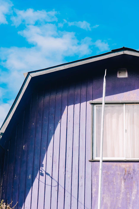 A close-up of a house roof painted in bright, eye-catching colors under a clear blue sky.