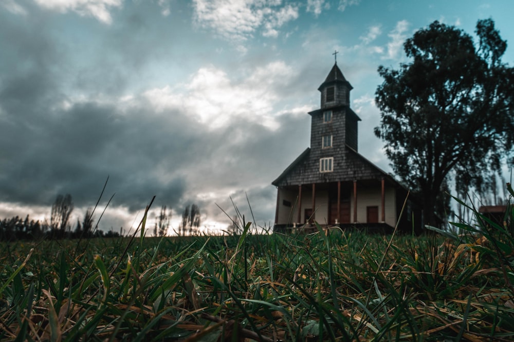 a church in the middle of a field under a cloudy sky