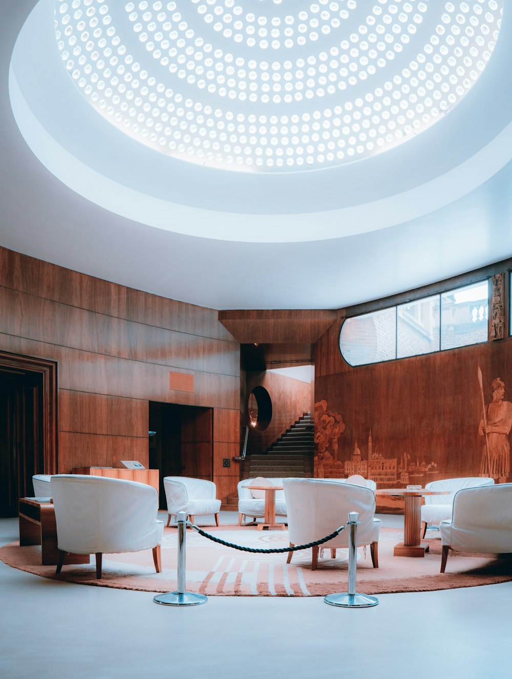 a room with a circular ceiling and white chairs