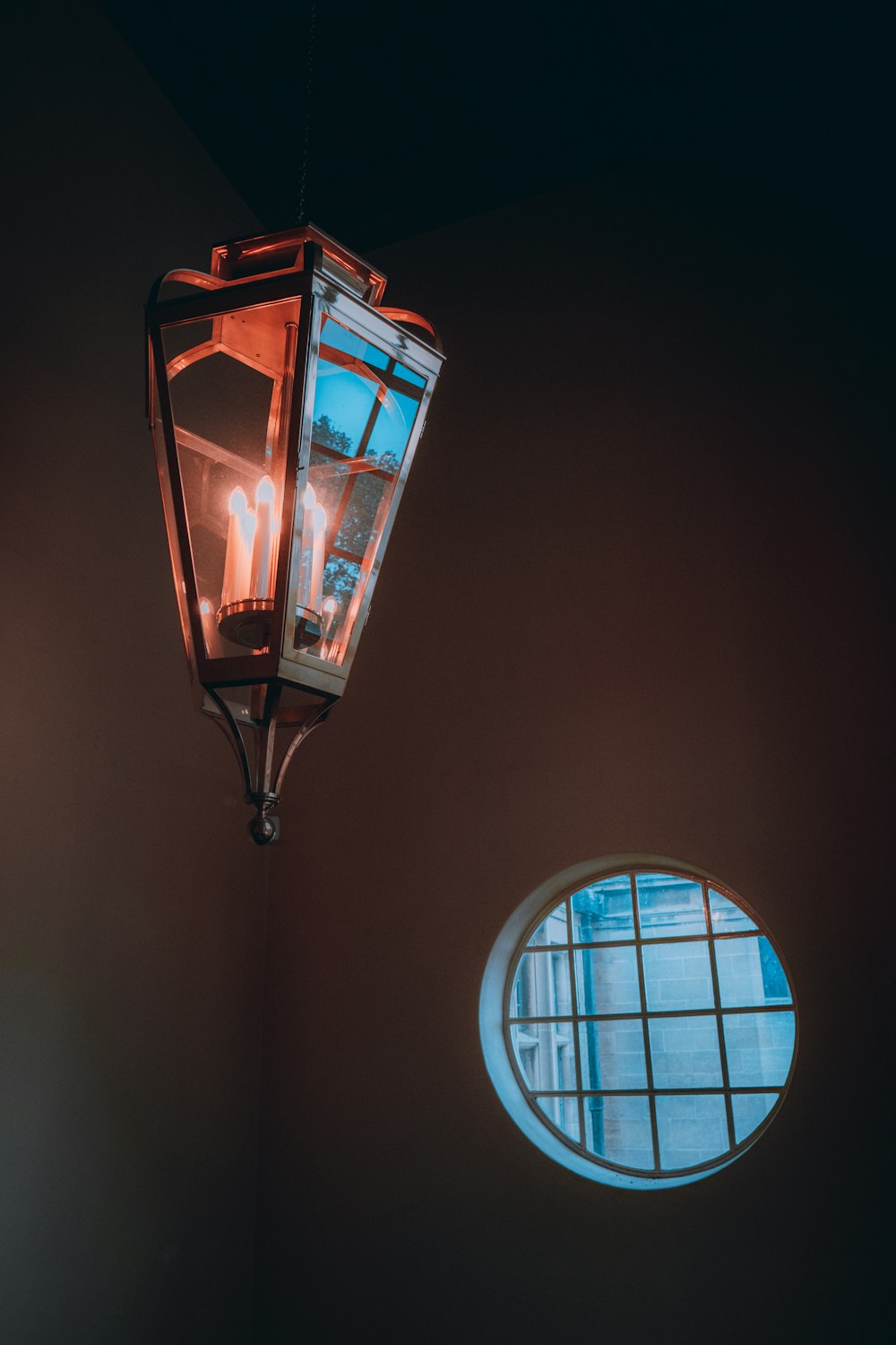 a lamp hanging from a ceiling next to a round window