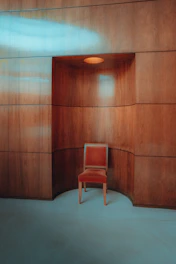 A handcrafted wooden chair with smooth curves and a soft cushion in a bright, minimalistic room.