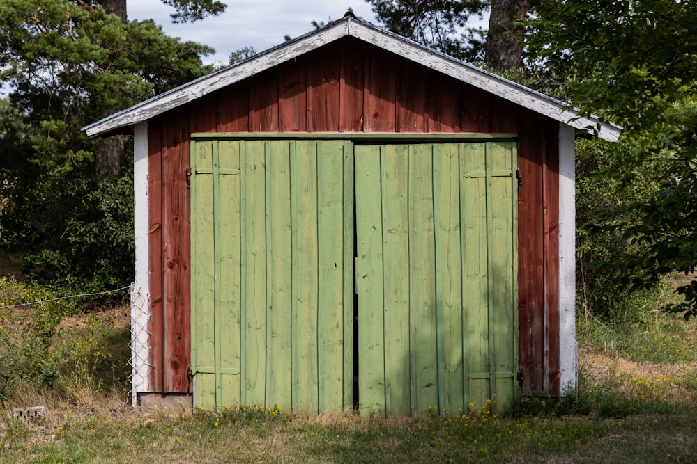 a red and green shed sitting in the middle of a field