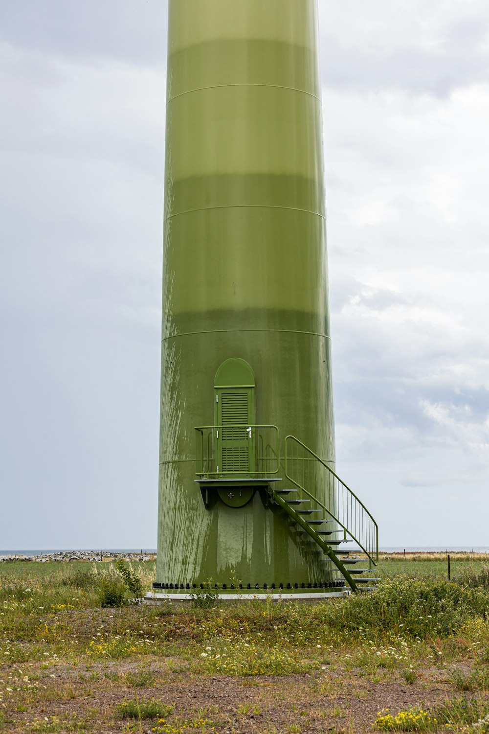 a large green tower with a staircase leading to it