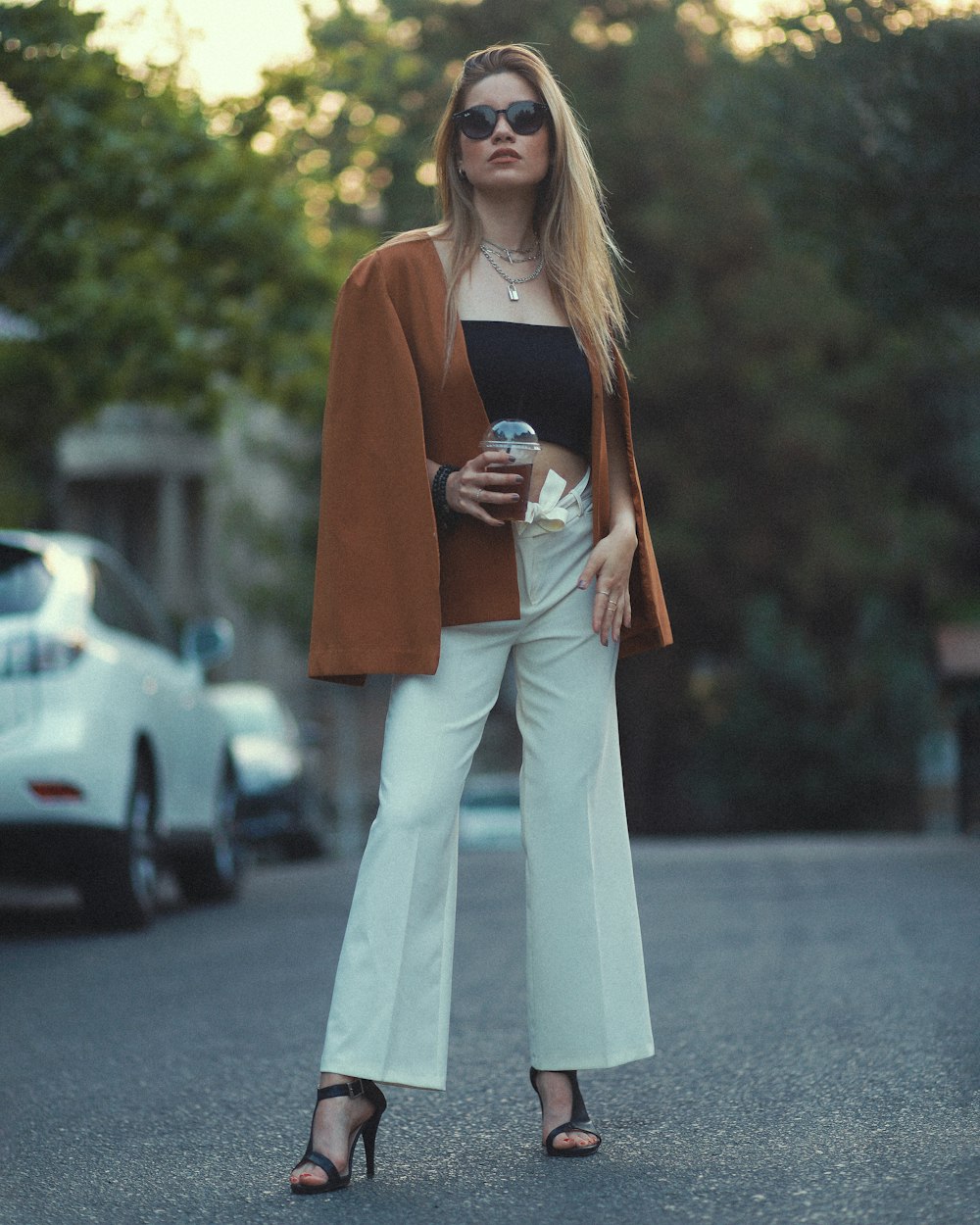 une femme en pantalon blanc et veste marron