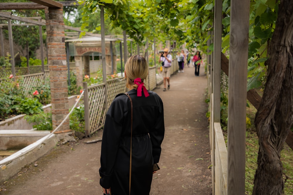 a woman walking down a path in a garden