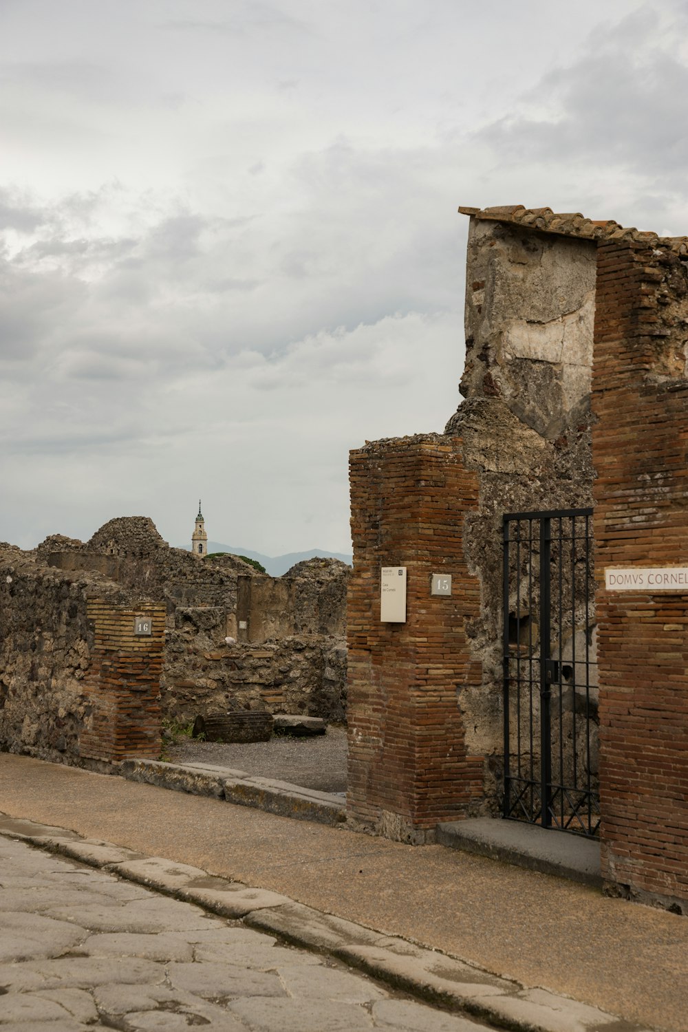 an old brick building with a gate and a clock tower in the background