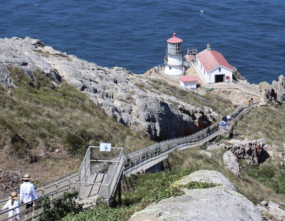 a couple of people walking up a hill next to a lighthouse