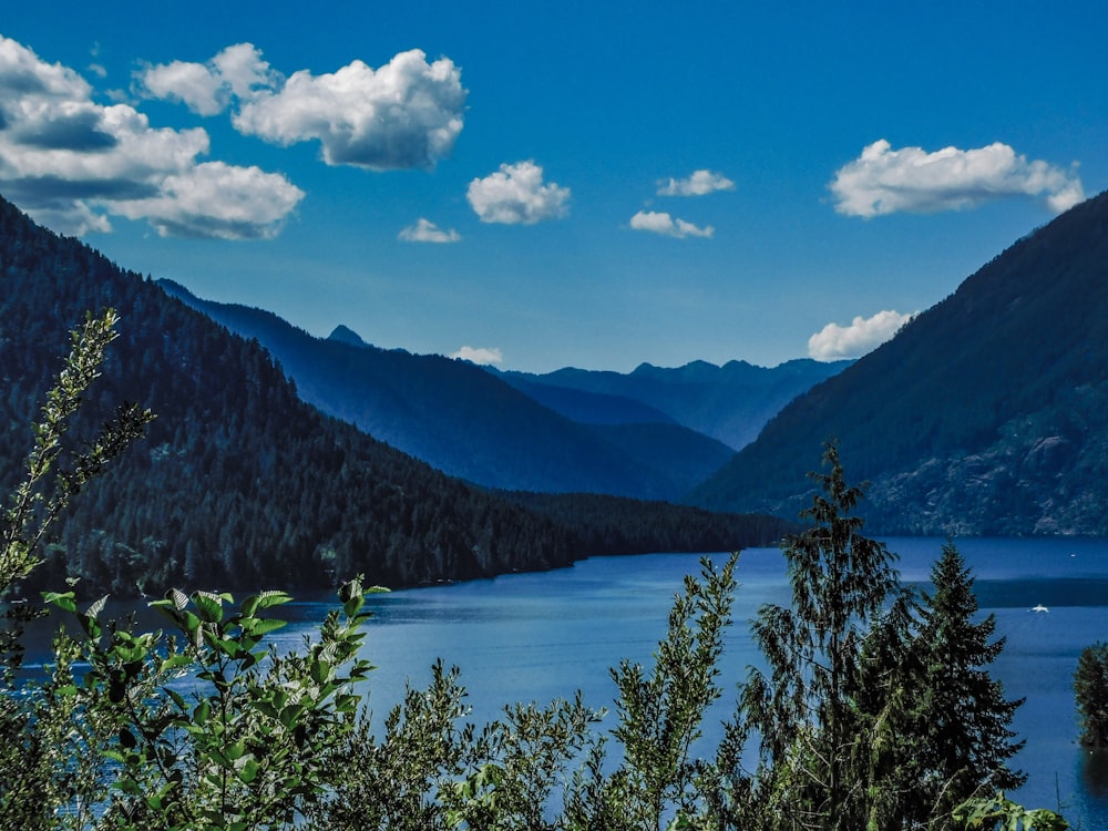 a lake surrounded by mountains under a blue sky