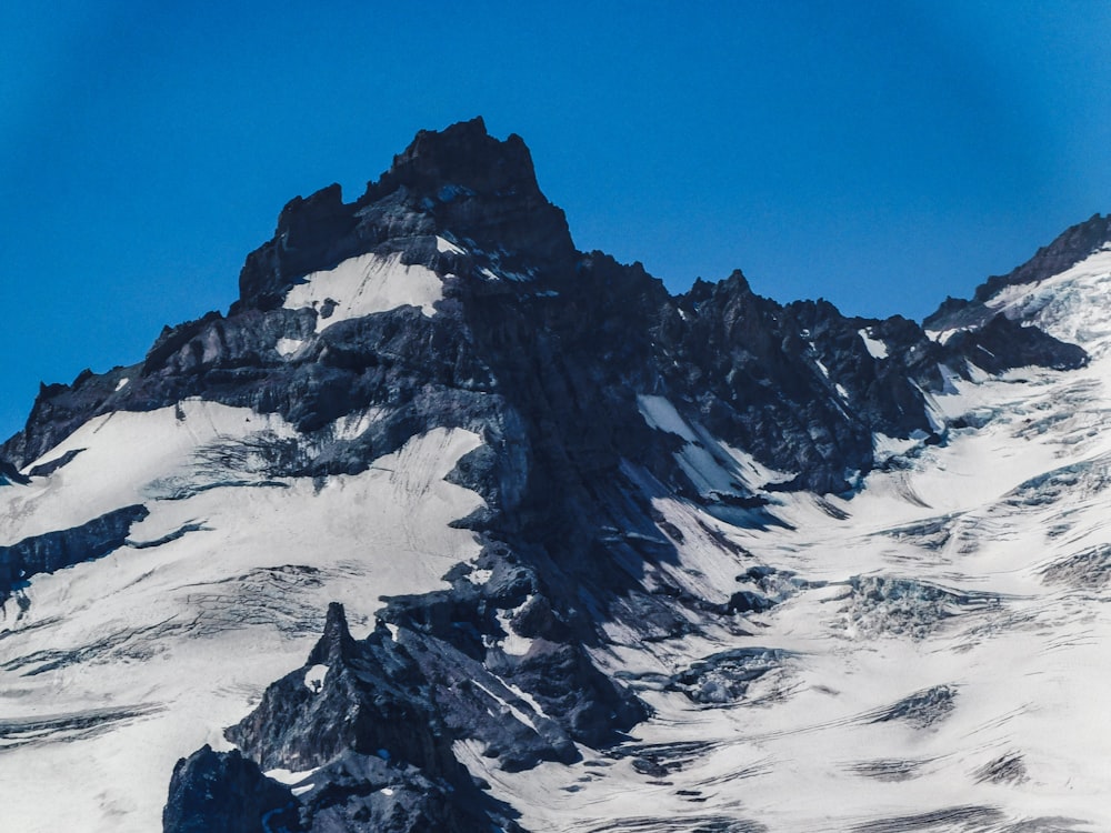 a large mountain covered in snow under a blue sky