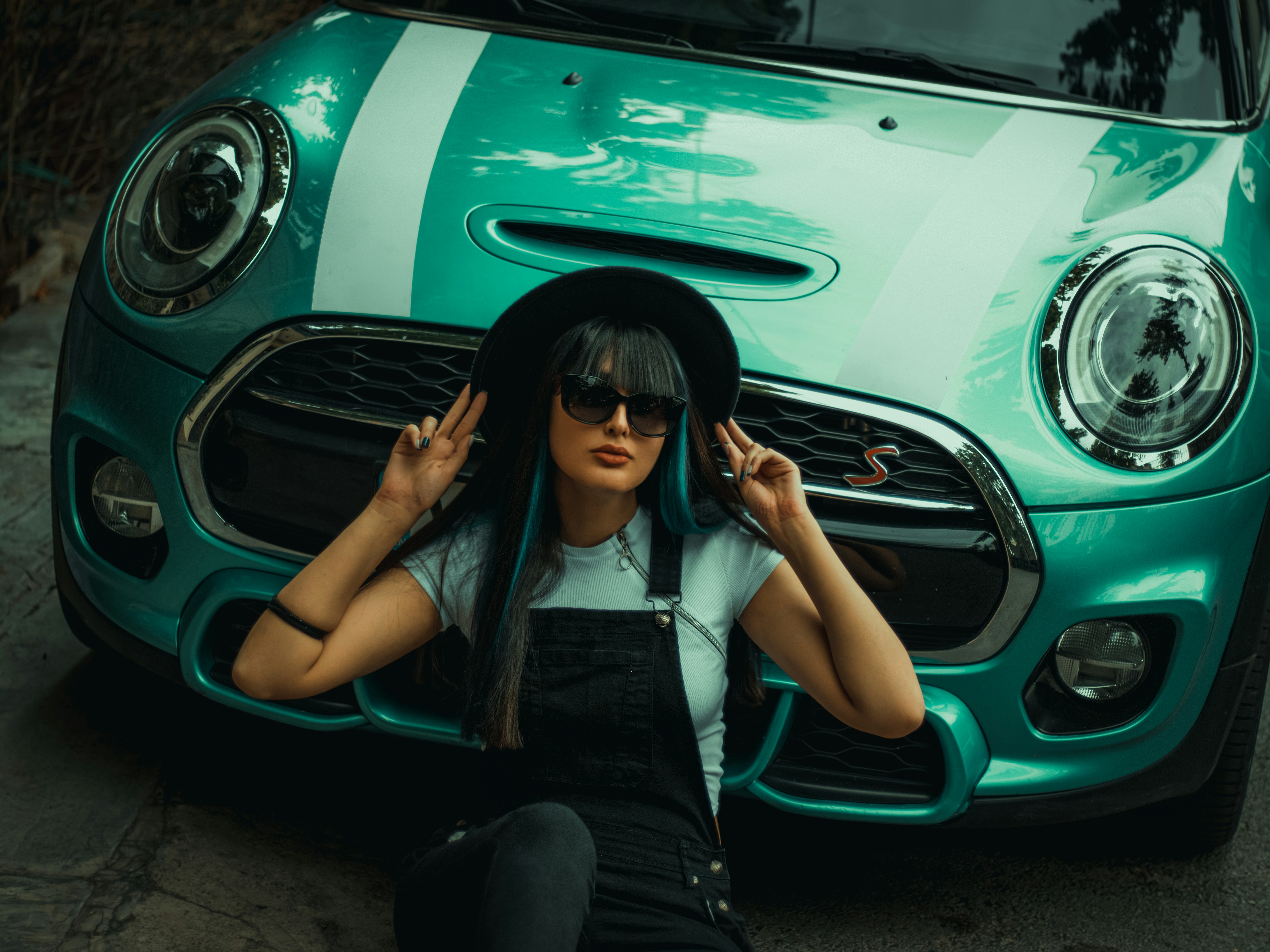 a woman sitting on the ground next to a green car