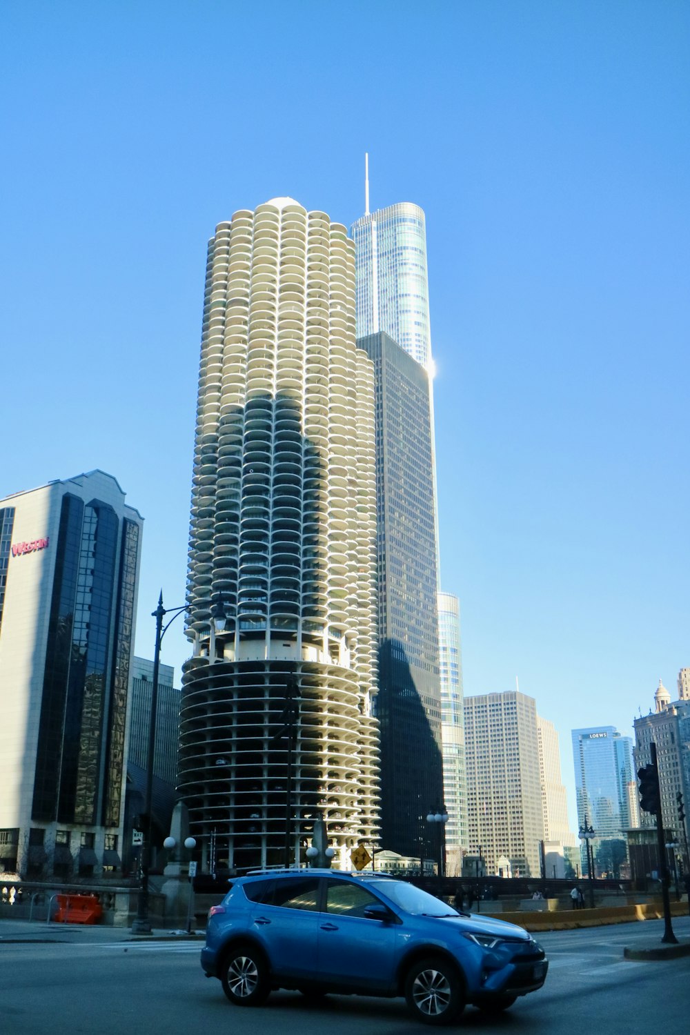 a blue car driving down a street next to tall buildings