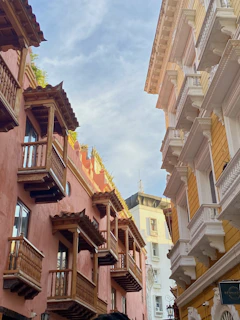 Historic old town street with pastel-colored buildings, wrought iron balconies, and blooming flowers