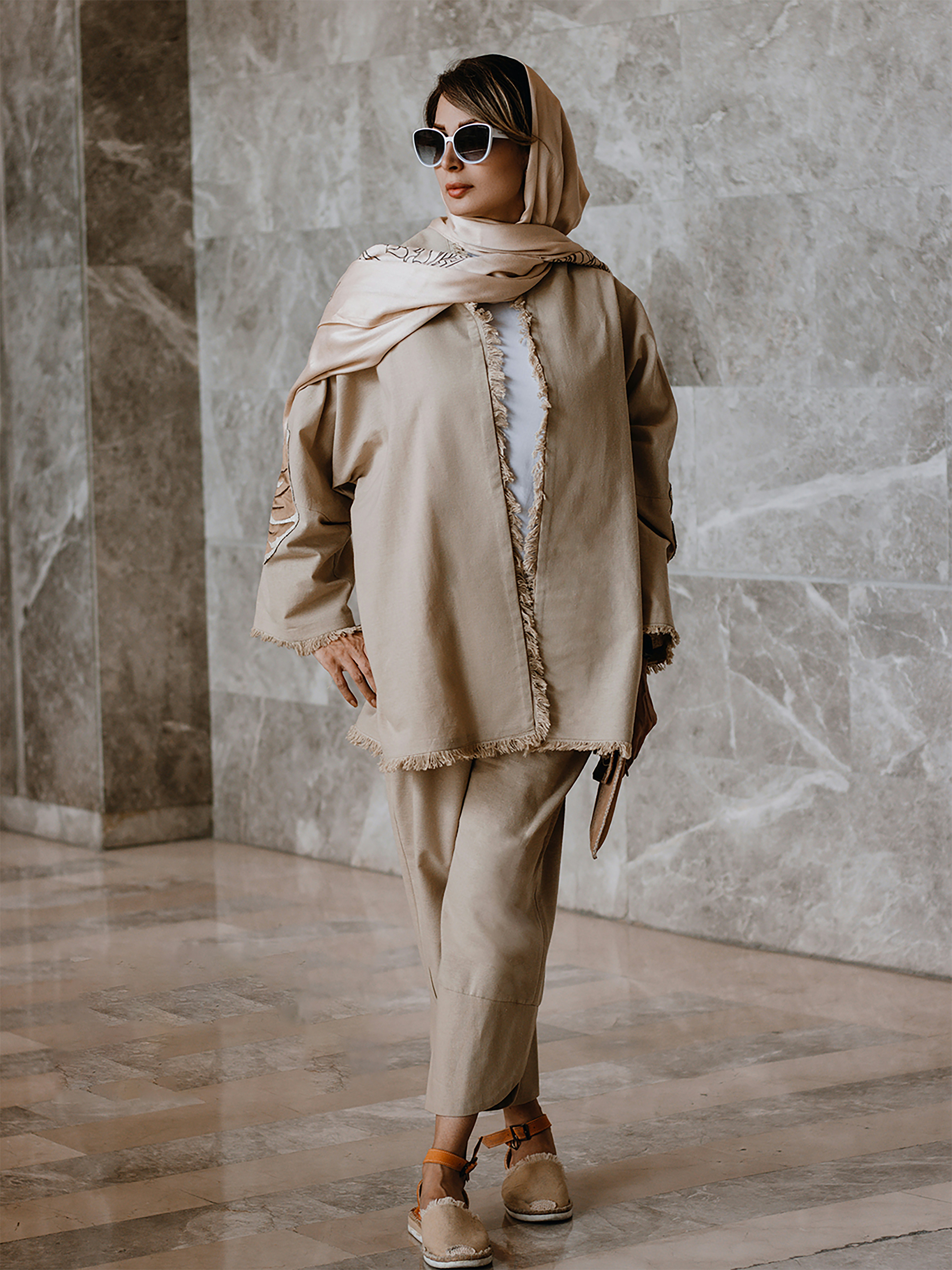 a woman in a beige outfit and sunglasses