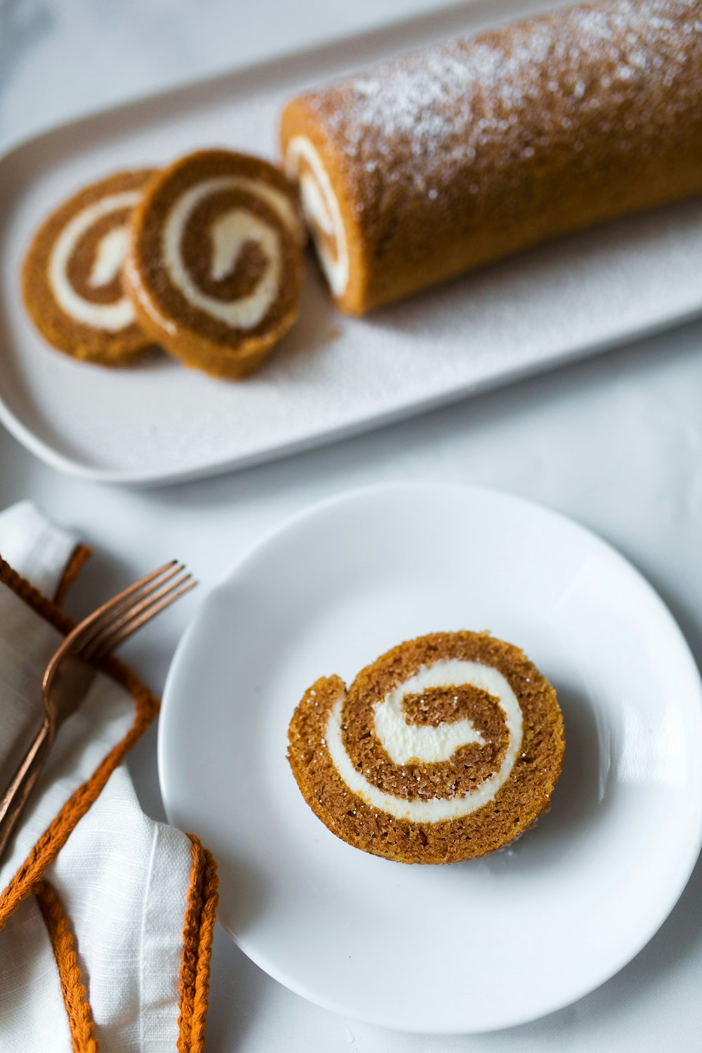 a cinnamon roll on a plate next to a fork