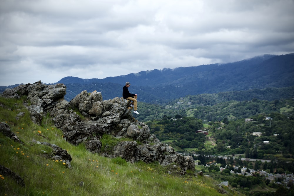 a man sitting on top of a rocky cliff