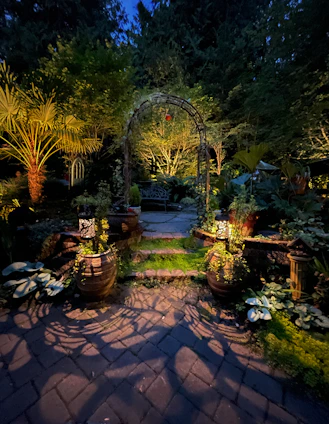 A peaceful garden pathway lined with glowing lanterns and soft flowers under a twilight sky.