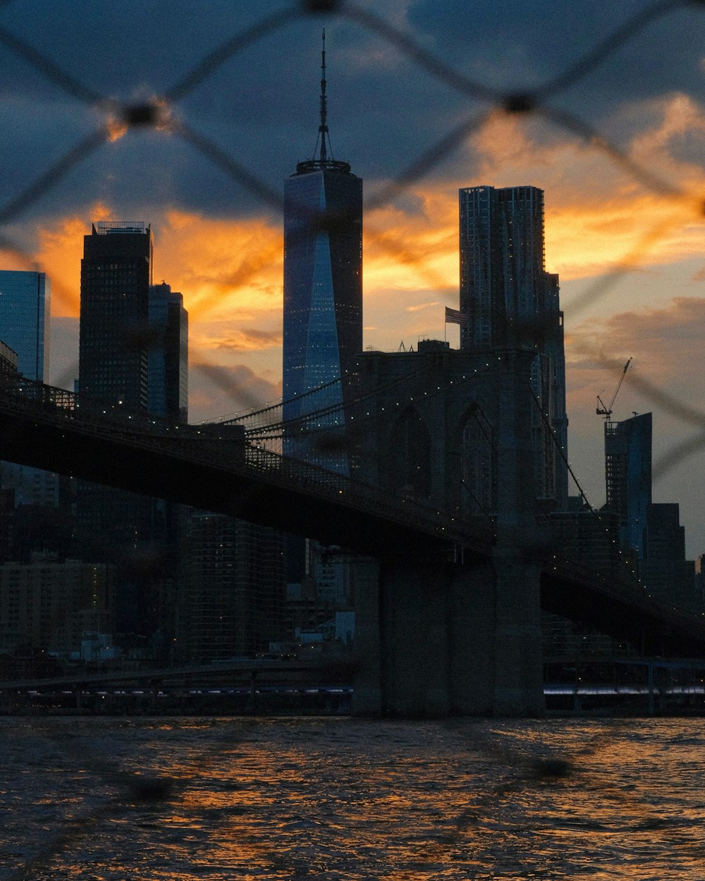 a view of a city skyline through a chain link fence