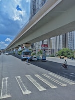 a man riding a bike down a street under a bridge