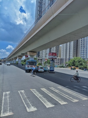 a man riding a bike down a street under a bridge