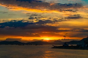 A vibrant sunset over a calm sea with silhouetted boats.