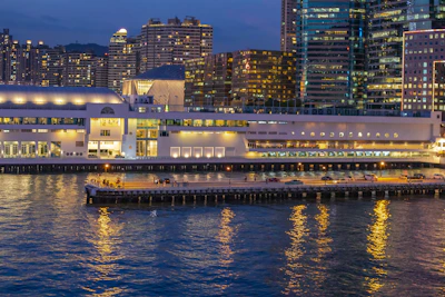 High-rise mixed-use development glowing warmly at dusk by the waterfront.
