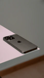 A sleek smartphone resting on a white surface with blue and orange accents in the background.