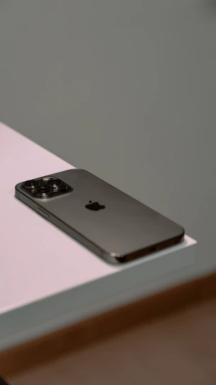 A sleek smartphone resting on a white surface with blue and orange accents in the background.