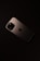 A smartphone with a sleek, metallic finish is placed on a dark surface. The device features a prominent camera module with multiple lenses and an Apple logo in the center.