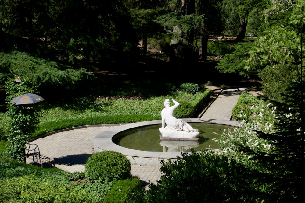 a garden with a fountain and a statue