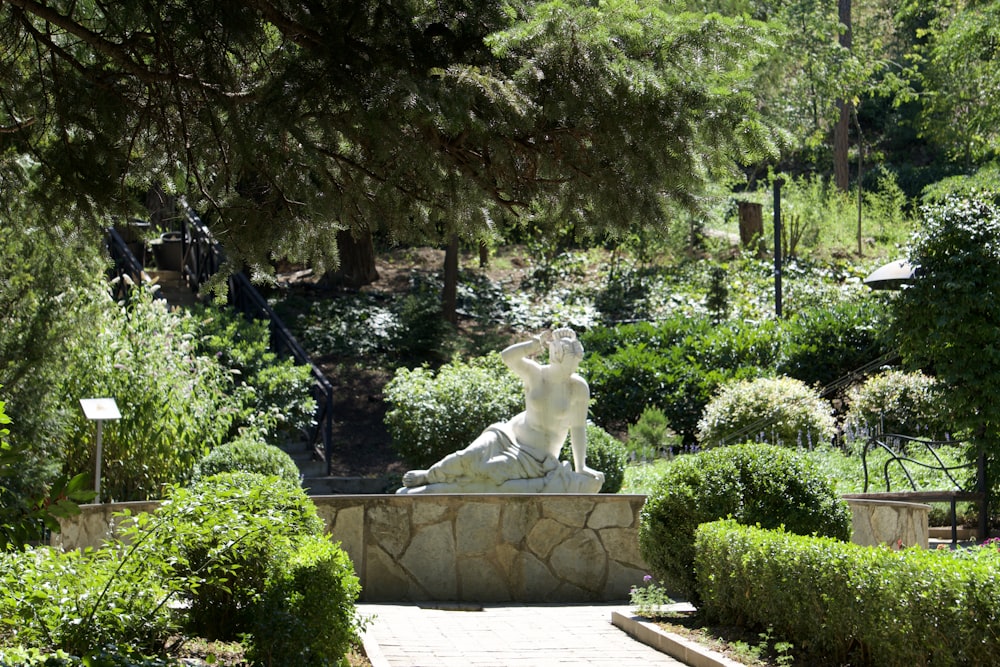 a statue of a woman sitting on a rock in a garden