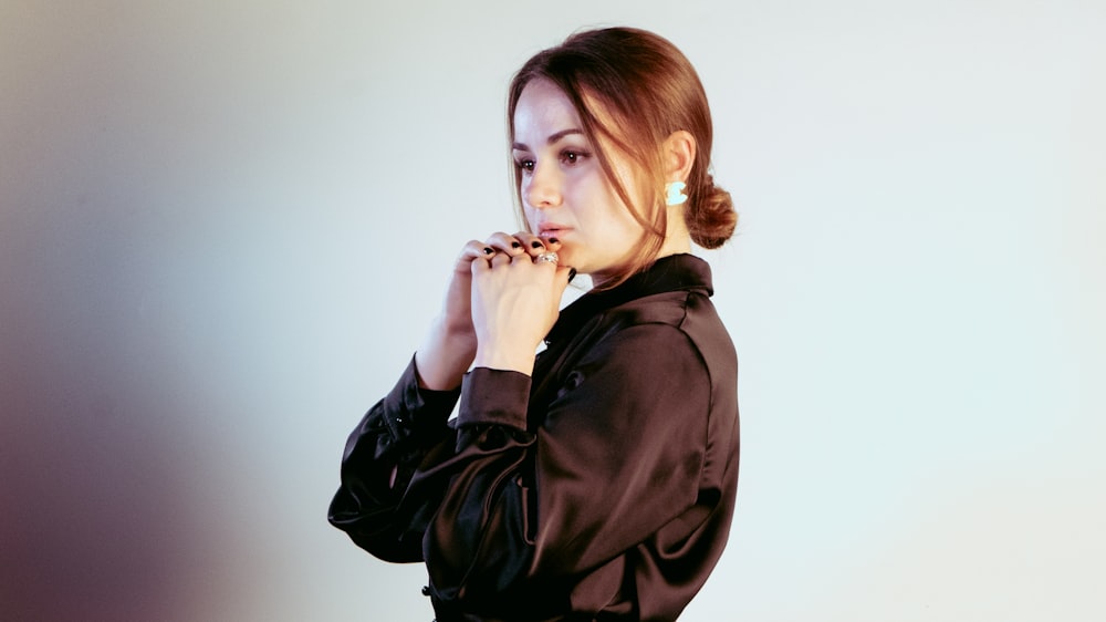 a woman in a black shirt is holding her hands together