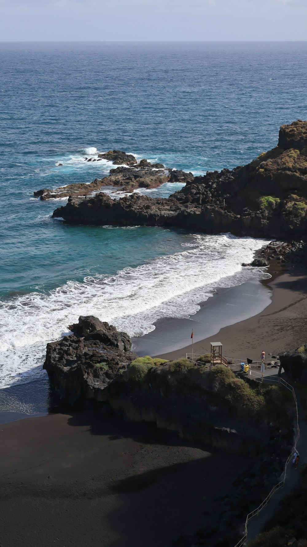 une plage de sable noir avec des vagues arrivant sur le rivage