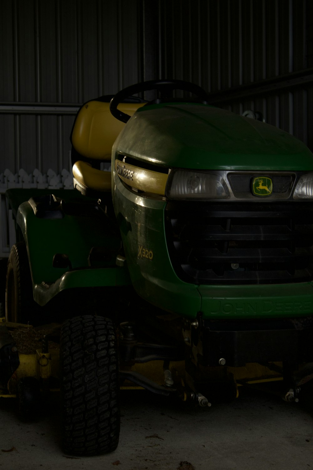 a green tractor parked inside of a garage