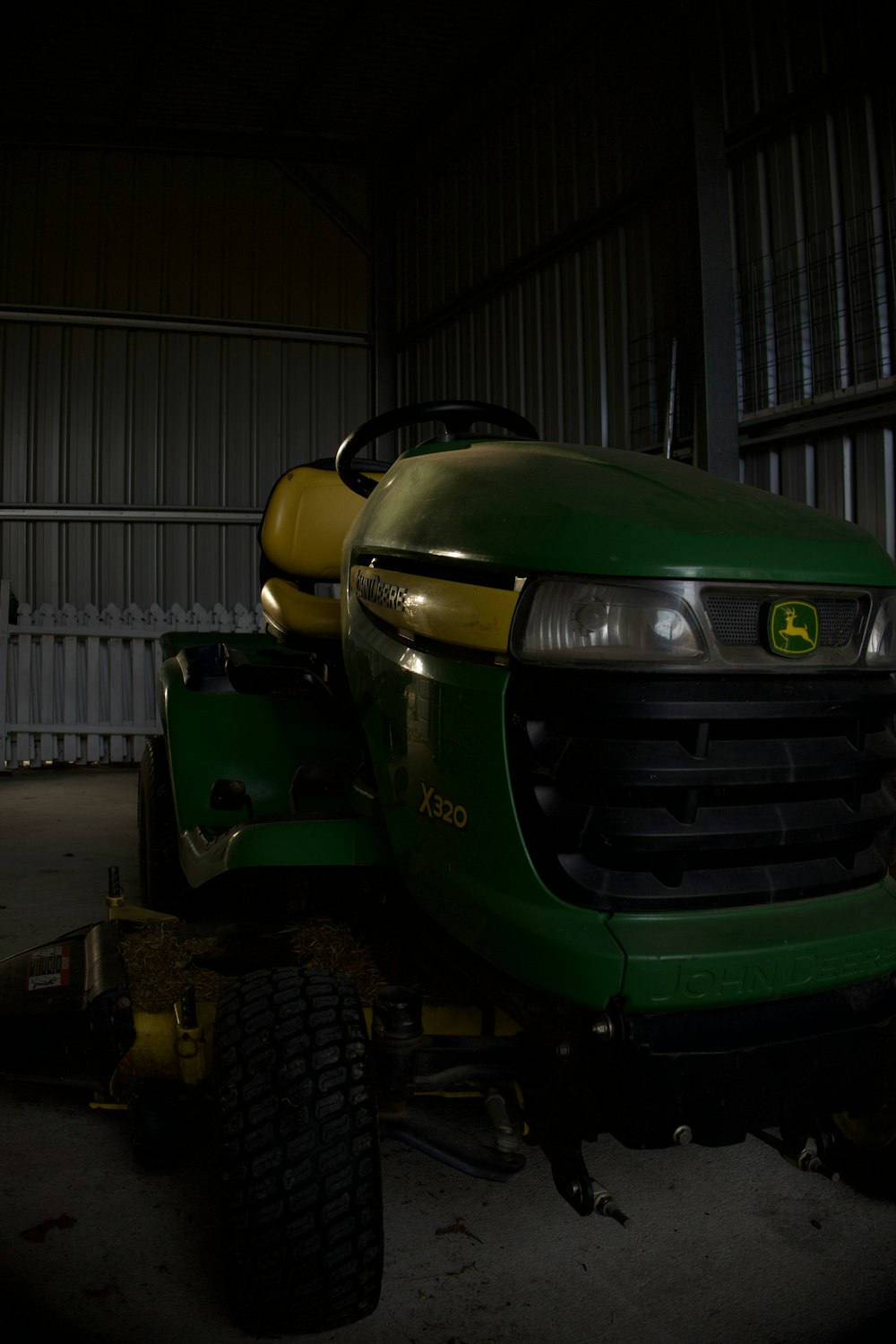 a green lawn mower parked in a garage