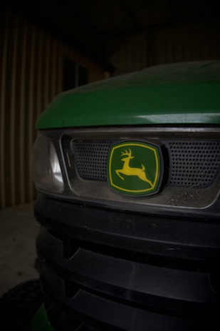 Close-up of a green tractor or machinery with a prominent logo in the center, depicting a leaping deer inside a green and yellow emblem.