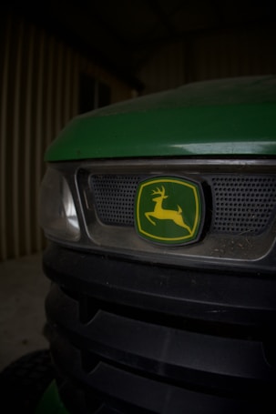 Close-up of a green tractor or machinery with a prominent logo in the center, depicting a leaping deer inside a green and yellow emblem.